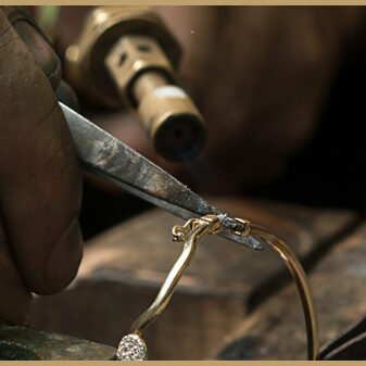 Jeweler melting gold bracelet with gasoline burner for making je